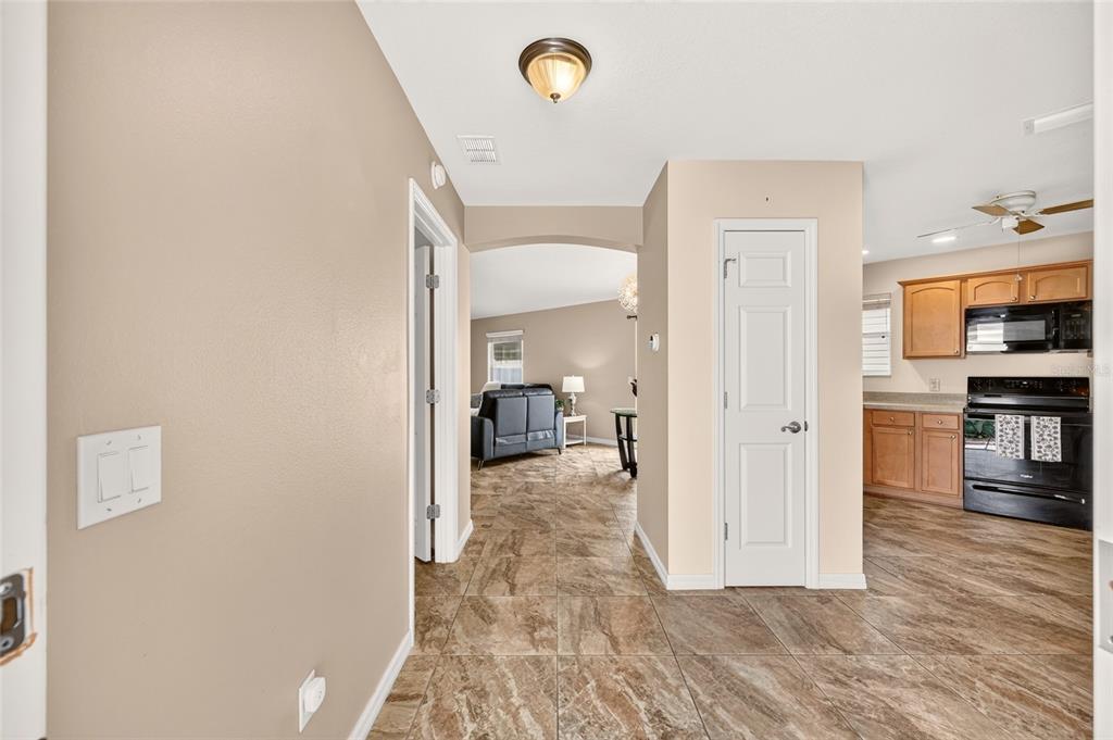 A tiled hallway leads to a living area with a kitchen visible on the right — 1813 HORTENSIA PLACE, THE VILLAGES, FL