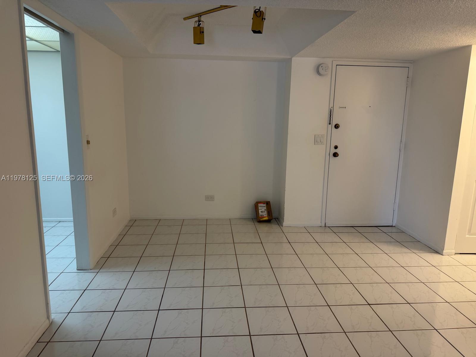 An empty room features white tiled floors, white walls, and a recessed ceiling light fixture — 3720 Inverrary Dr # 2K, Lauderhill FL 33319, LAUDERHILL, FL