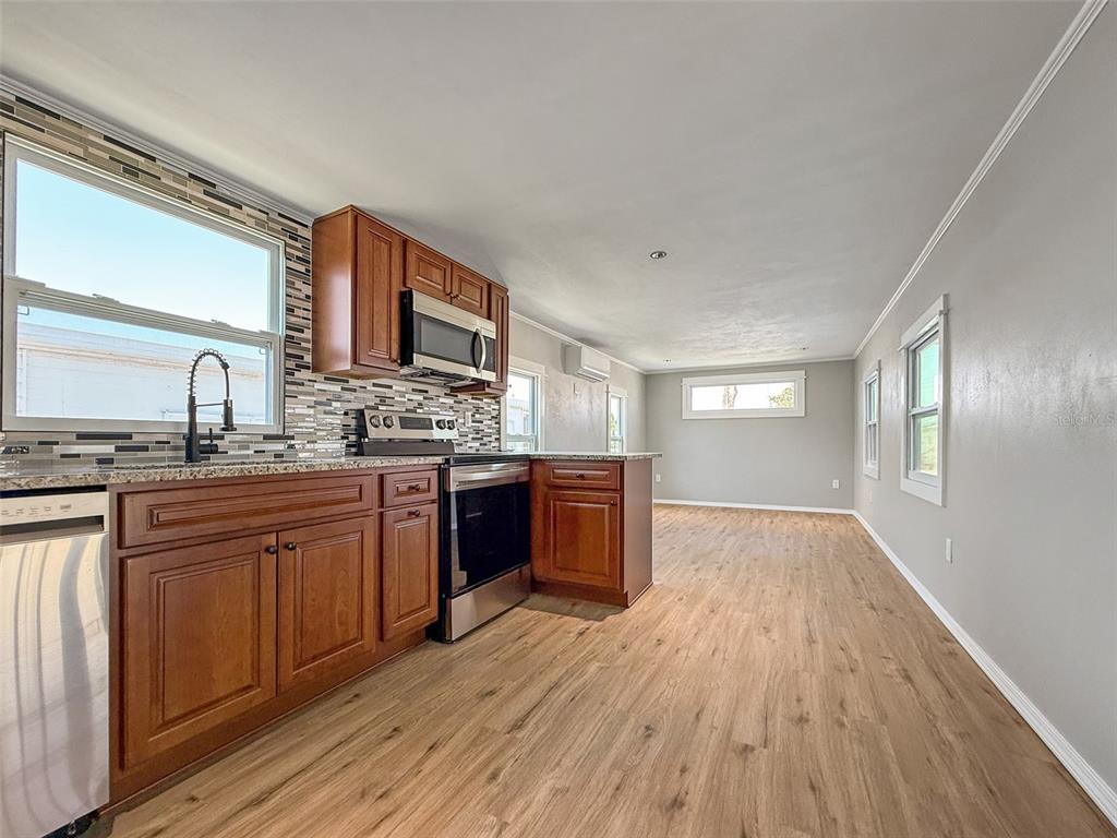 A kitchen with wood cabinets and stainless steel appliances opens into a living area — 5141 OAKLAND HILLS AVENUE, SARASOTA, FL