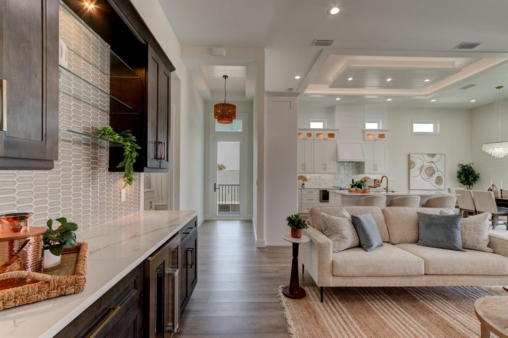 A view of a kitchen and living area with dark cabinetry, white countertops, and wood flooring — 6555 ENGRAM ROAD, NEW SMYRNA BEACH, FL