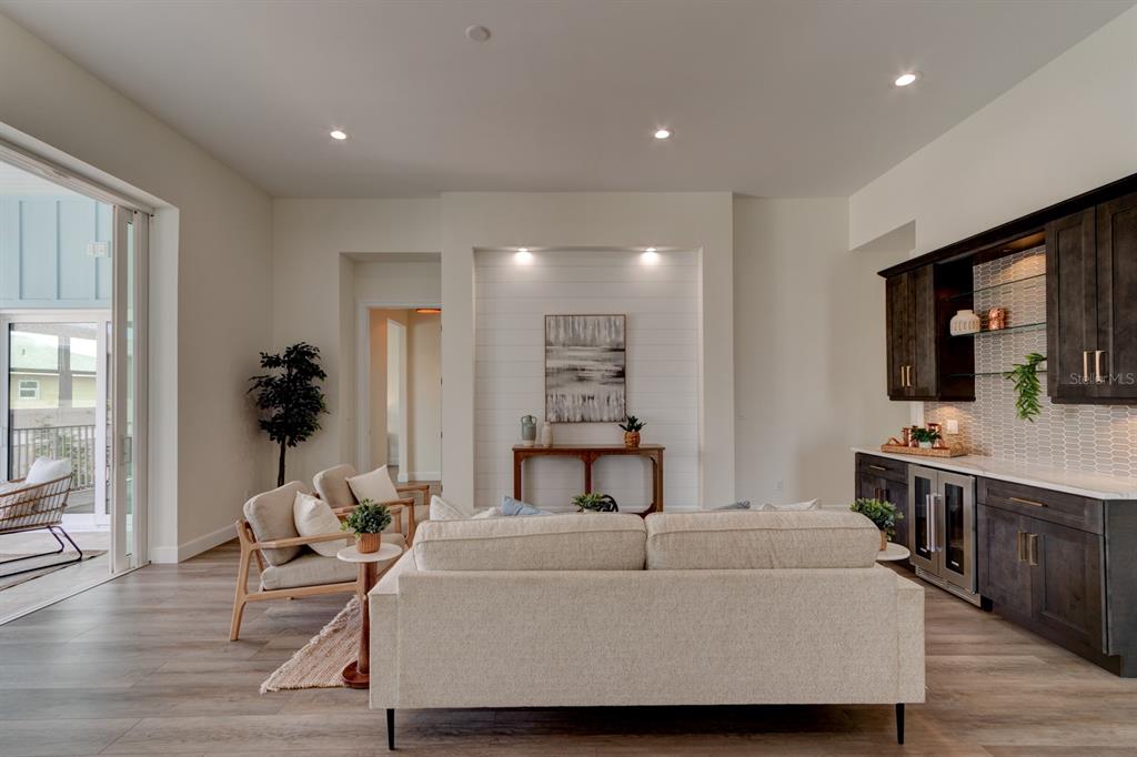 A living room features a sofa, two armchairs, a wet bar, and shiplap wall accents — 6555 ENGRAM ROAD, NEW SMYRNA BEACH, FL