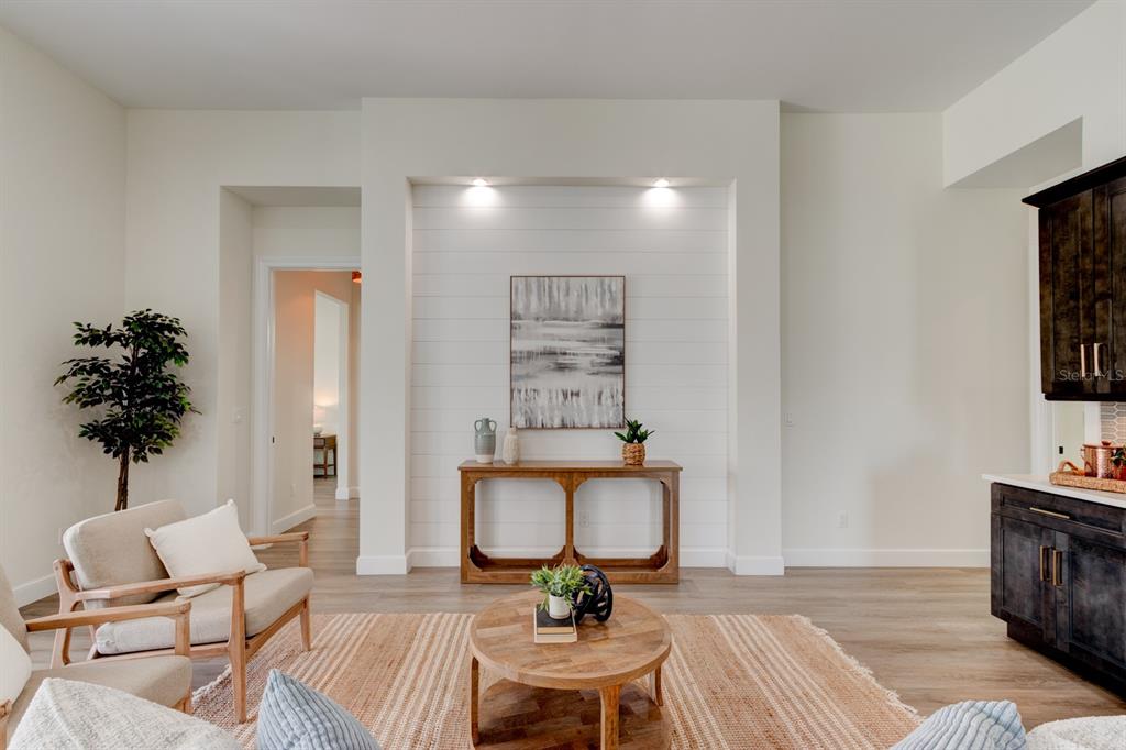 A living room features a shiplap accent wall, wood flooring, and a round coffee table — 6555 ENGRAM ROAD, NEW SMYRNA BEACH, FL