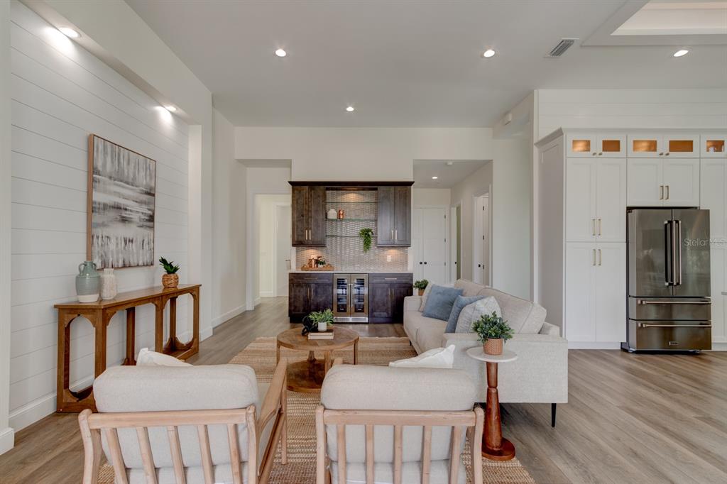 A living room features white shiplap walls, a dark wood wet bar, and neutral furniture — 6555 ENGRAM ROAD, NEW SMYRNA BEACH, FL