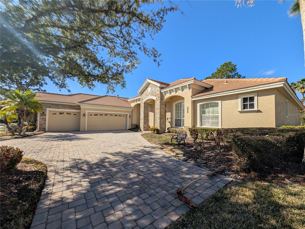 A single-story house with a stone-accented entryway, a paver driveway, and a three-car garage — 8492 DUNHAM STATION DRIVE, TAMPA, FL