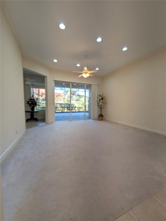 A spacious living room features beige carpeting, recessed lighting, a ceiling fan, and sliding glass doors — 8492 DUNHAM STATION DRIVE, TAMPA, FL