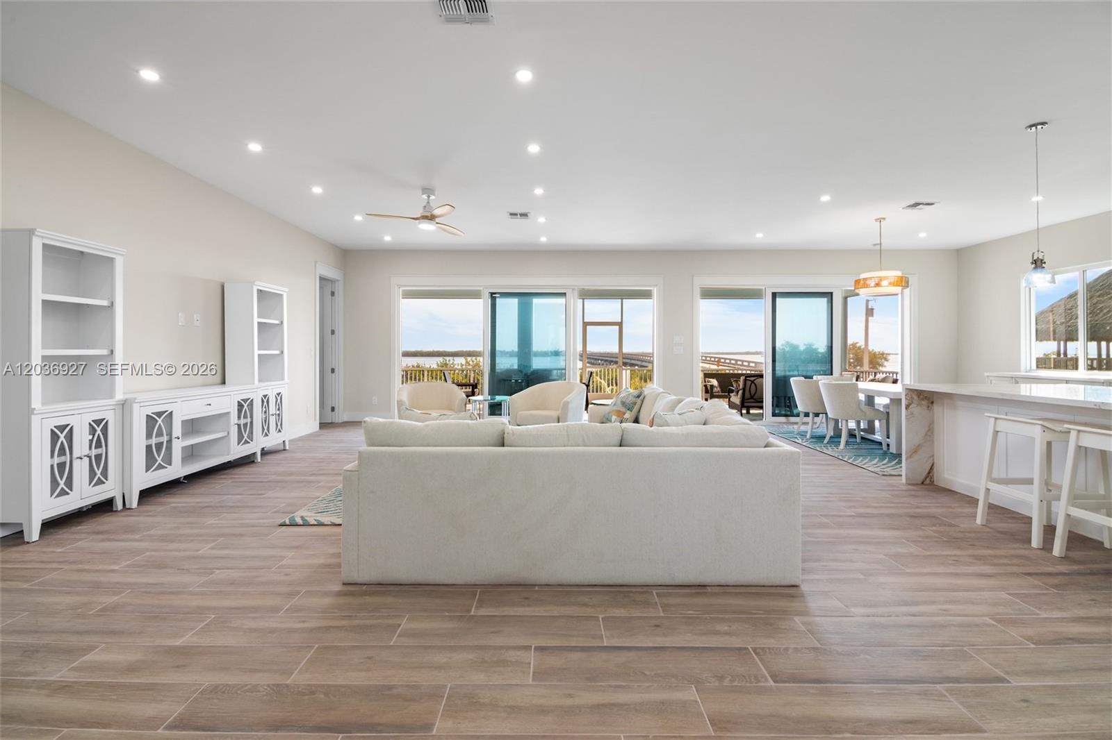 A bright, open-concept living and dining area features light wood-look tile flooring and water views — 30995 Watson Blvd, Big Pine FL 33043, BIG PINE, FL