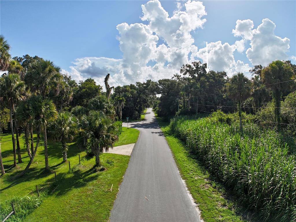 An aerial view shows a paved road winding through a lush, tree-lined landscape — 15306 SW PALM OAK AVENUE, INDIANTOWN, FL