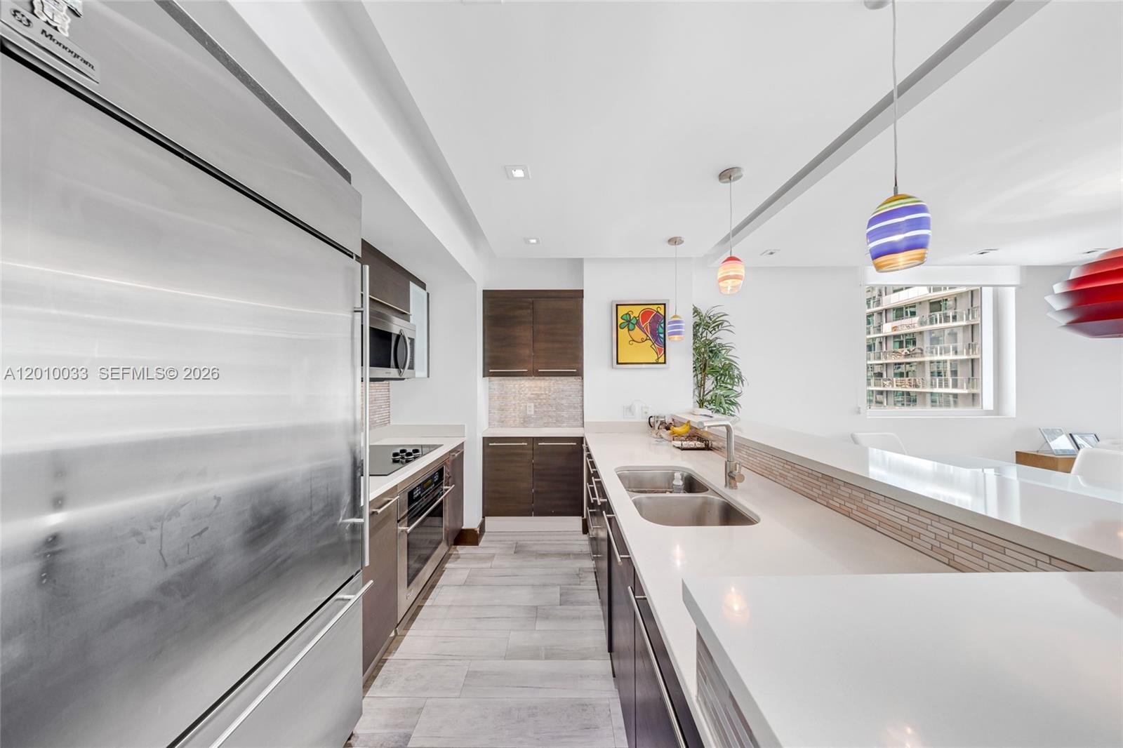 A modern kitchen features dark wood cabinetry, stainless steel appliances, and white quartz countertops — 500 Brickell Ave # 3707, Miami FL 33131, MIAMI, FL