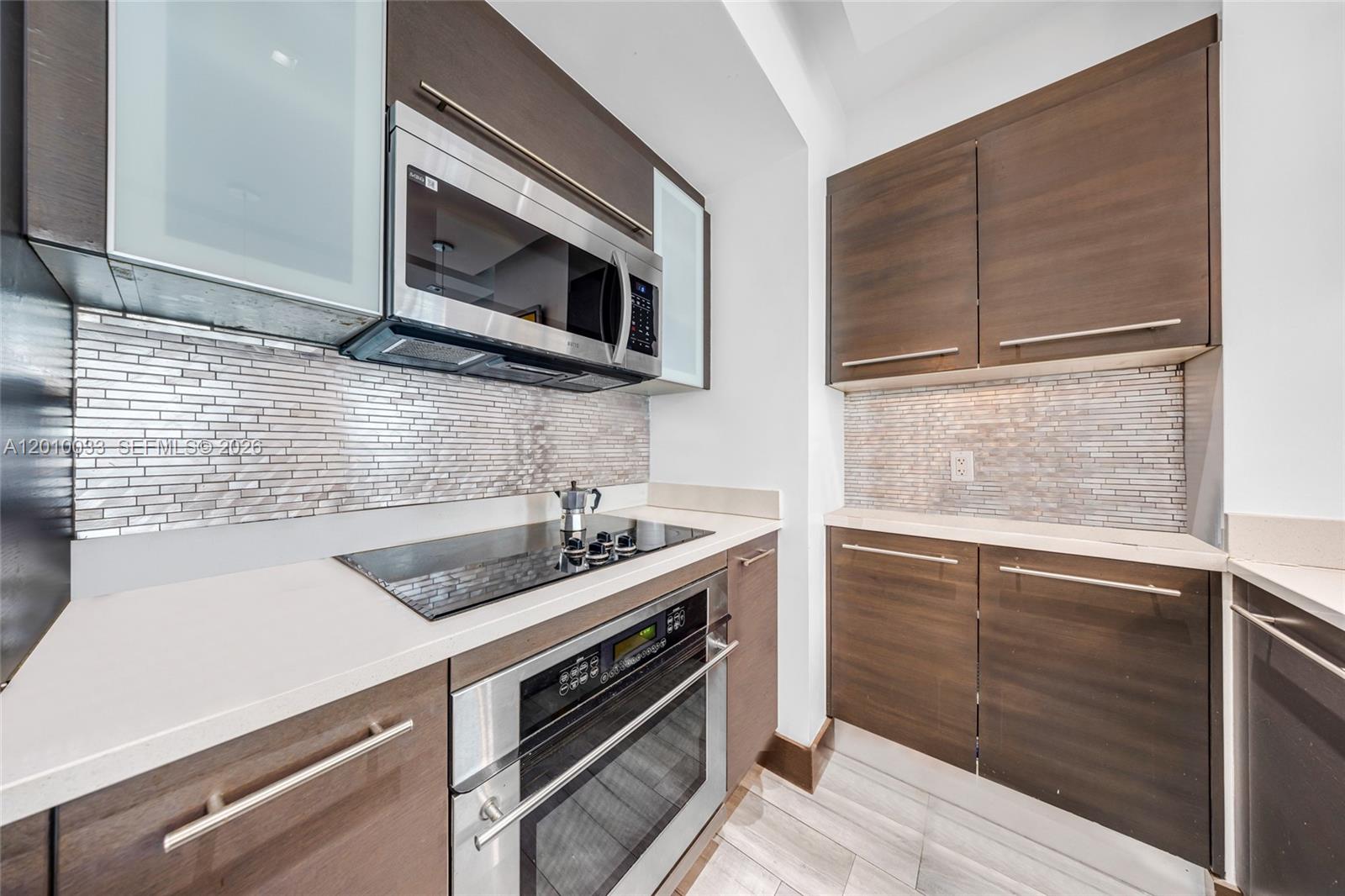 A modern kitchen features dark wood cabinets, stainless steel appliances, and a tiled backsplash — 500 Brickell Ave # 3707, Miami FL 33131, MIAMI, FL