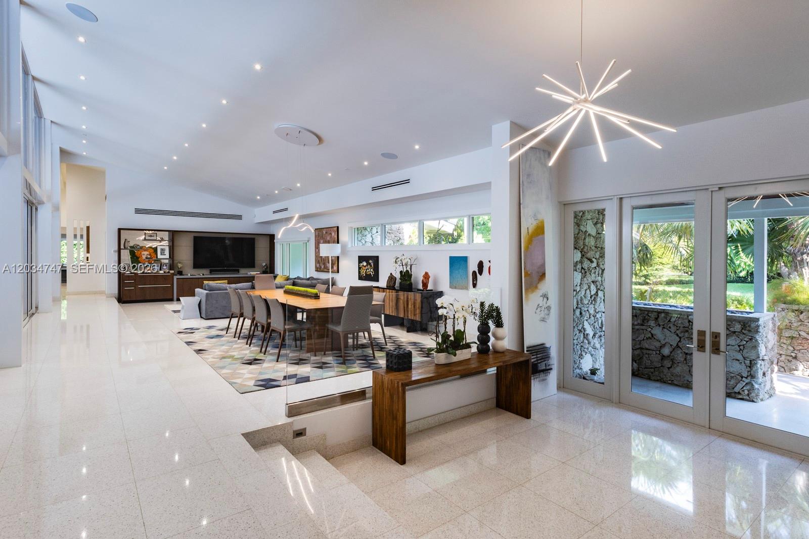 A spacious, open-concept living and dining area features white tile floors and a sunken floor — 5780 Las Palmas Dr, Coral Gables FL 33156, CORAL GABLES, FL