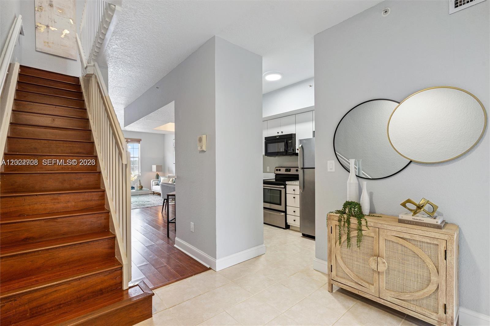 A wooden staircase leads up beside a kitchen and a hallway with a console table — 745 SW 148th Ave # 804, Sunrise FL 33325, SUNRISE, FL