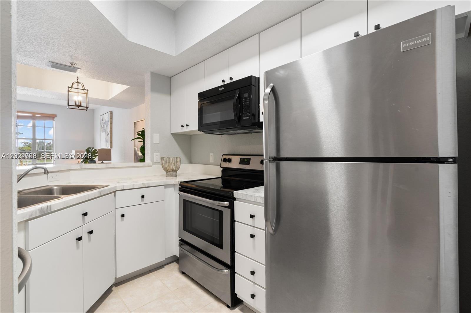 A kitchen features white cabinets, stainless steel appliances, and a pass-through window to a room — 745 SW 148th Ave # 804, Sunrise FL 33325, SUNRISE, FL