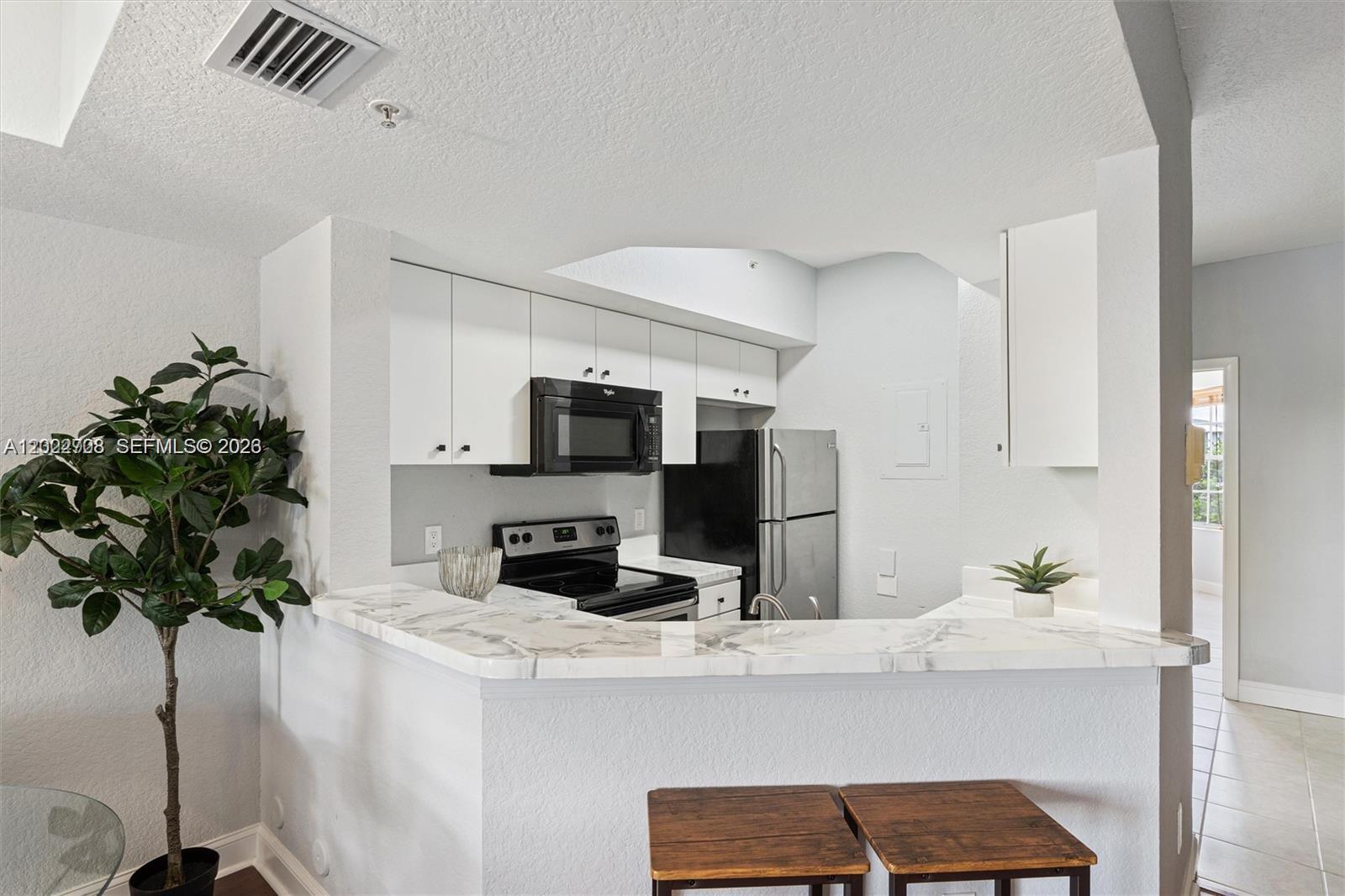 A kitchen features white cabinets, stainless steel appliances, and a marble-patterned breakfast bar — 745 SW 148th Ave # 804, Sunrise FL 33325, SUNRISE, FL