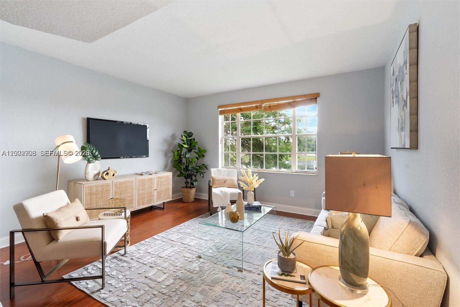 A living room features a glass coffee table, a beige sofa, and wood flooring — 745 SW 148th Ave # 804, Sunrise FL 33325, SUNRISE, FL