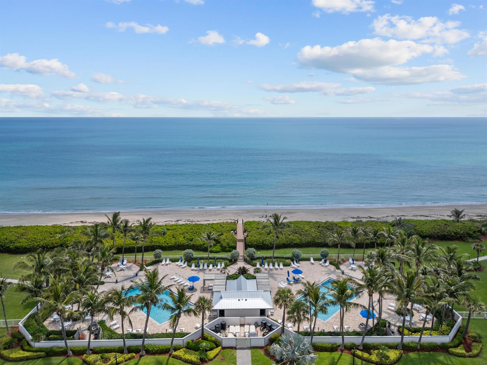 An aerial view shows two swimming pools and a clubhouse located near a beach — 8880 S Ocean Drive # 409, Jensen Beach FL 34957, JENSEN BEACH, FL