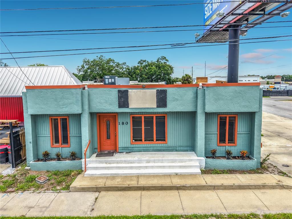 A teal, single-story commercial building with orange trim and a large billboard stands nearby — 180 S RONALD REAGAN BOULEVARD, LONGWOOD, FL