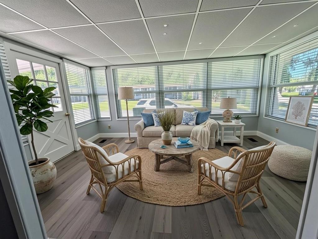 A sunroom features light gray wood-look flooring, a beige sofa, two rattan chairs, and blinds — 103 ROYAL PALM DRIVE, LEESBURG, FL