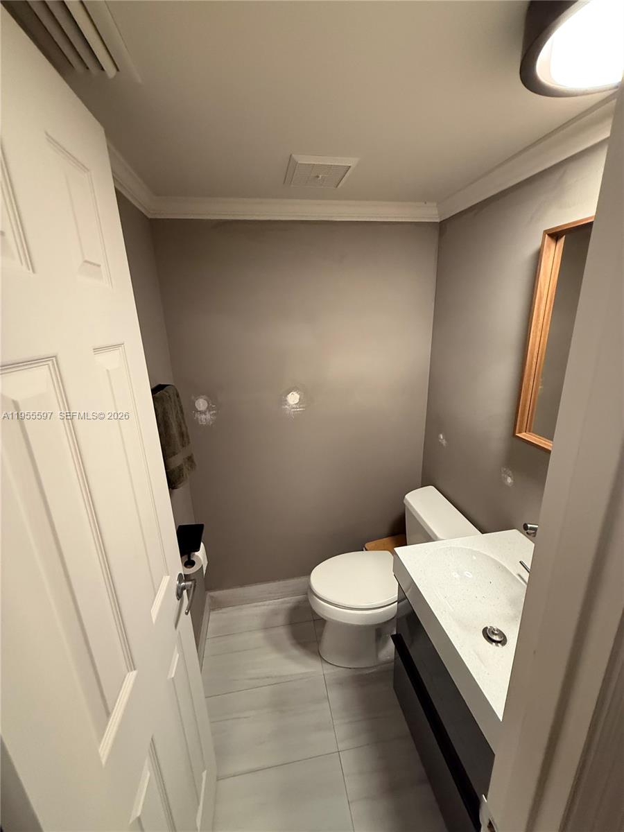 A small bathroom features a white vanity, a toilet, and gray walls with tile flooring — 7765 SW 86th St # 112, Miami FL 33143, MIAMI, FL