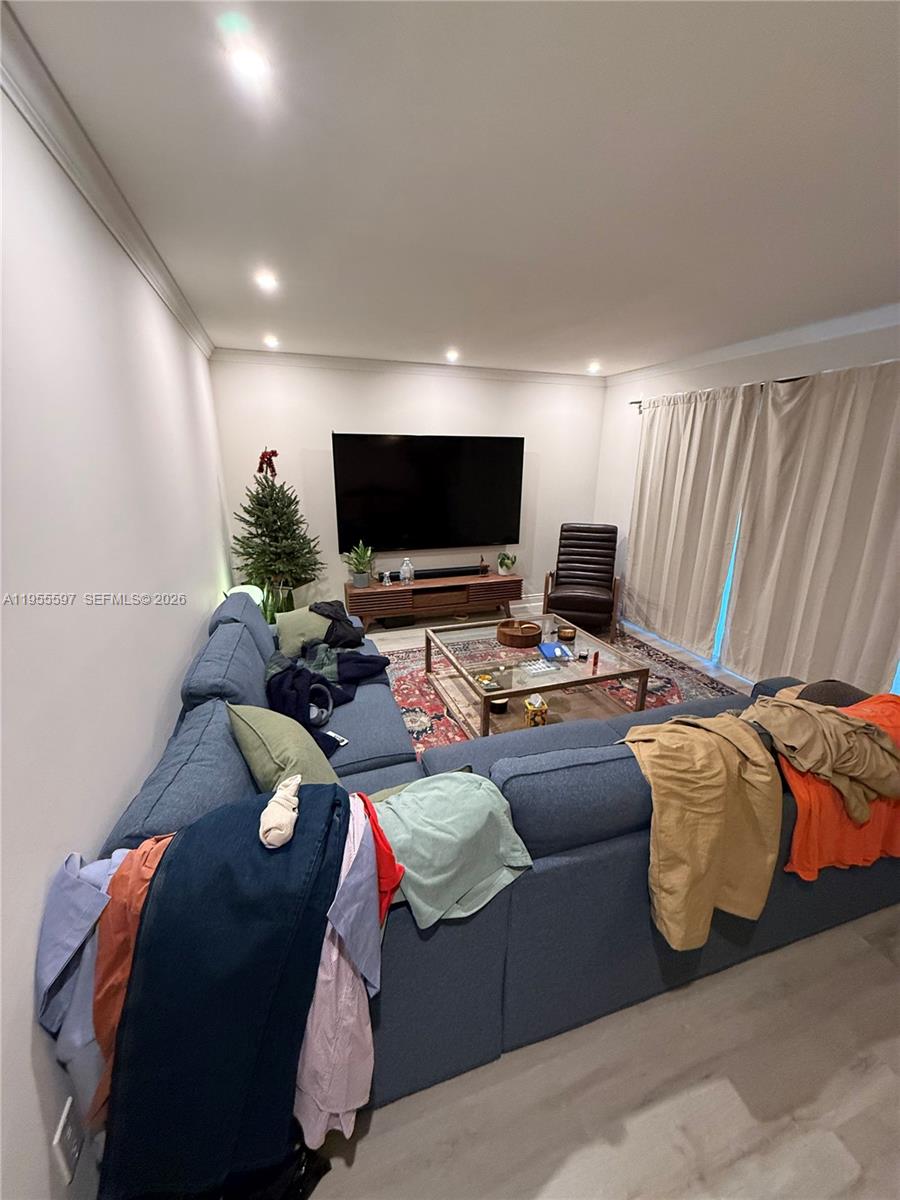A living room features a blue sectional sofa, a glass coffee table, and a wall-mounted television — 7765 SW 86th St # 112, Miami FL 33143, MIAMI, FL