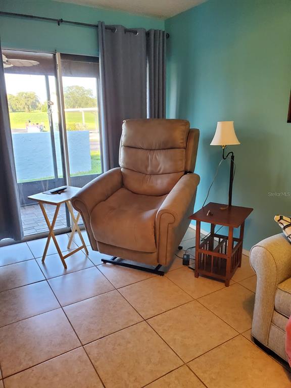 A living room features a tan recliner, two side tables, and a sliding glass door — 11135 CARRIAGE HILL DRIVE UNIT 3, PORT RICHEY, FL