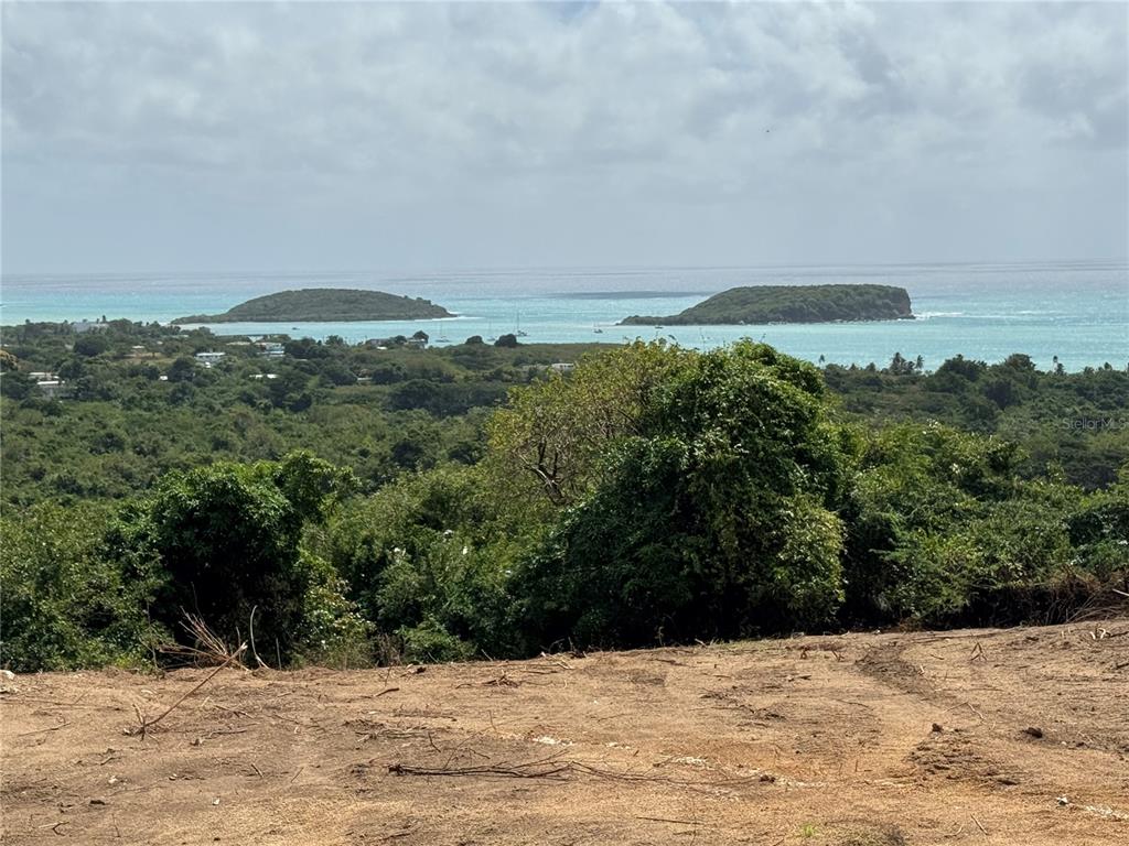 A view of two islands in the ocean from a cleared, elevated dirt lot — A-1 FINCA VIEQUES, VIEQUES, PR