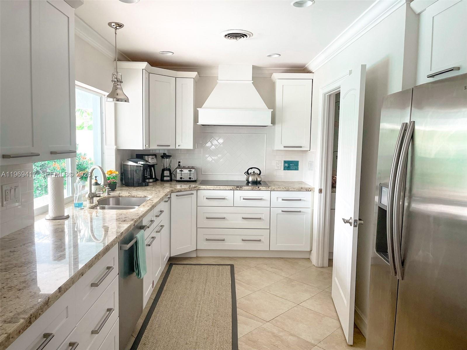 A kitchen features white cabinetry, granite countertops, stainless steel appliances, and a tiled floor — 2932 NE 36th St, Lighthouse Point FL 33064, LIGHTHOUSE POINT, FL