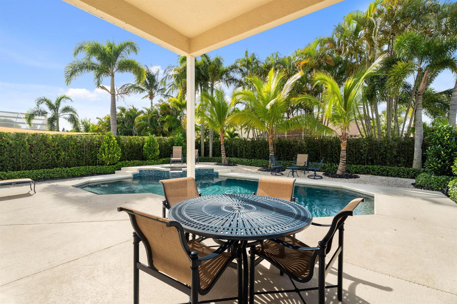 A patio with a dining set overlooks a swimming pool surrounded by palm trees — 4620 SE Winter Haven Court, Stuart FL 34997, STUART, FL