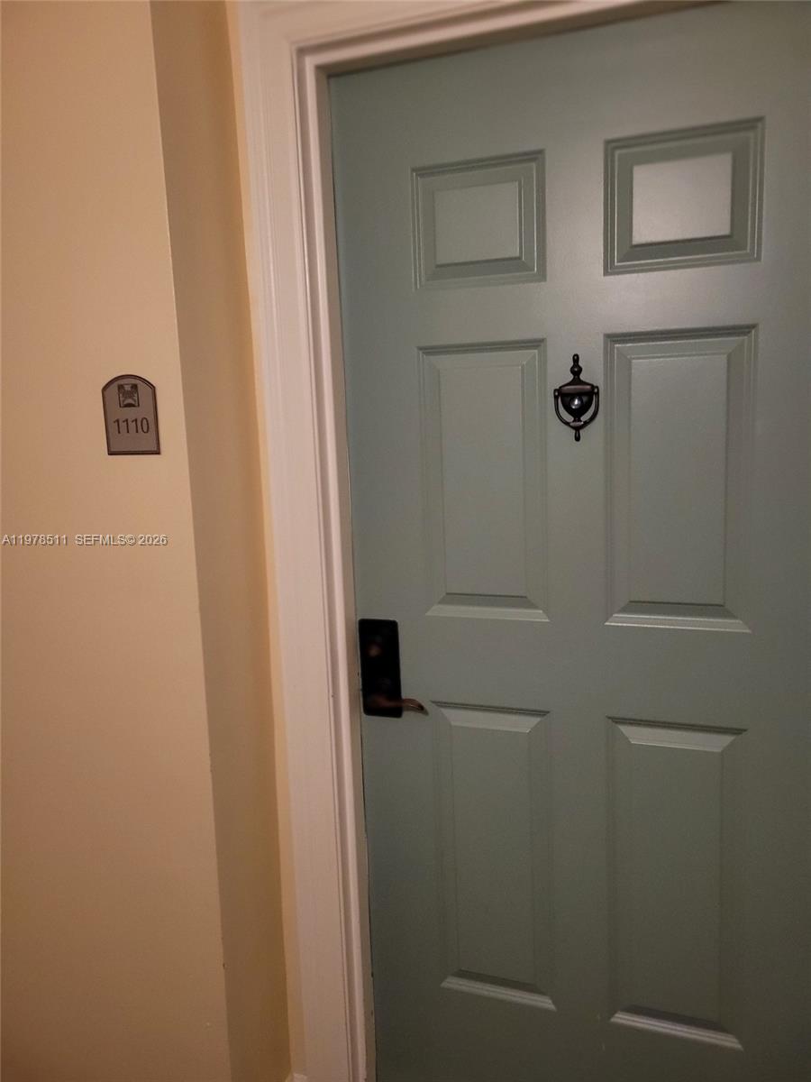 A light blue door with a black knocker and handle is labeled with unit number 1110 — 888 S Douglas Rd # 1110, Coral Gables FL 33134, CORAL GABLES, FL