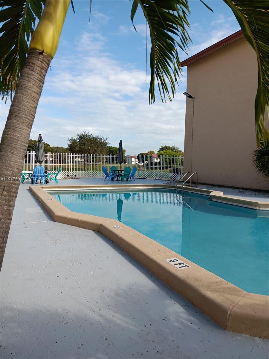 A swimming pool with a shallow end and patio seating area sits beside a building — 271 W Park Dr # 7, Miami FL 33172, MIAMI, FL
