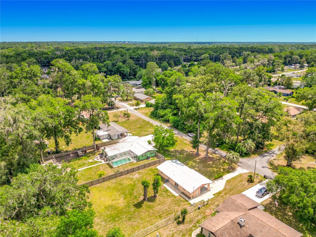 An aerial view shows several houses with yards, trees, and a swimming pool — 3309 NE 16TH AVENUE, OCALA, FL