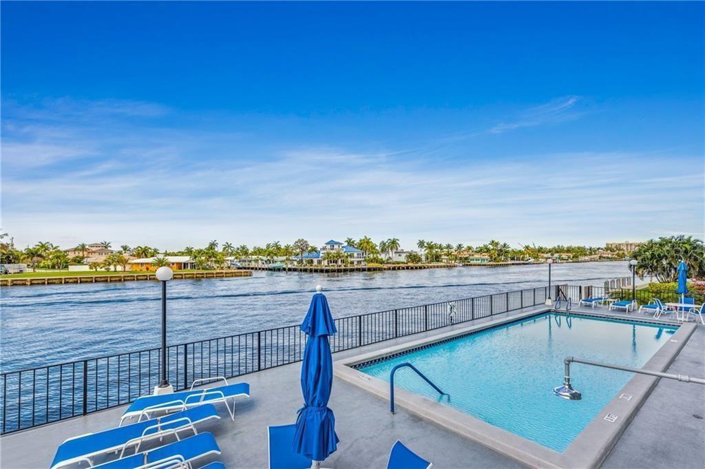 A swimming pool on a concrete deck overlooks a canal with houses in the distance — 521 N Riverside Drive # 602, Pompano Beach FL 33062, POMPANO BEACH, FL