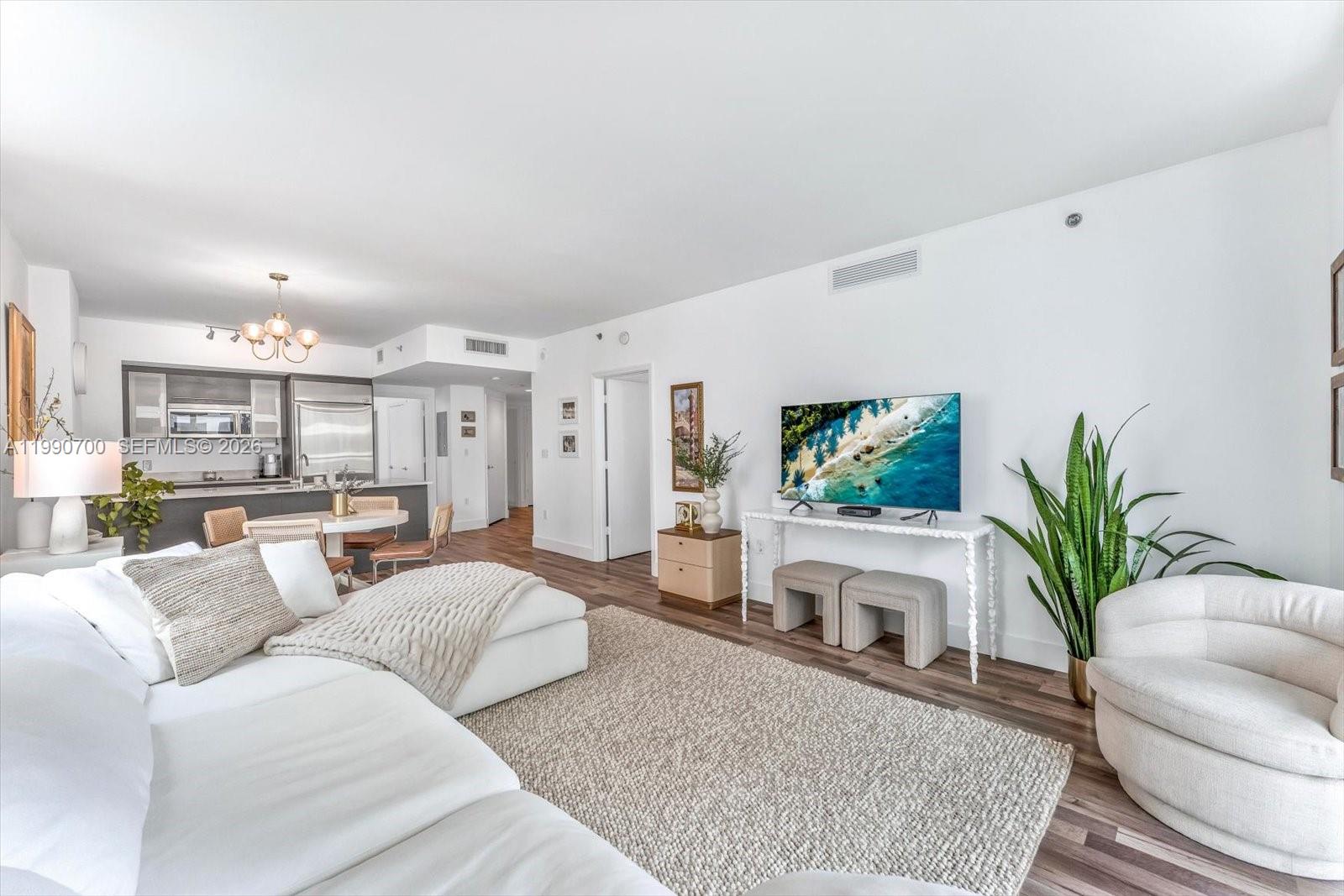 A living room with a white sectional sofa, television, and an adjacent open-concept kitchen — 500 Brickell Ave # 1810, Miami FL 33131, MIAMI, FL