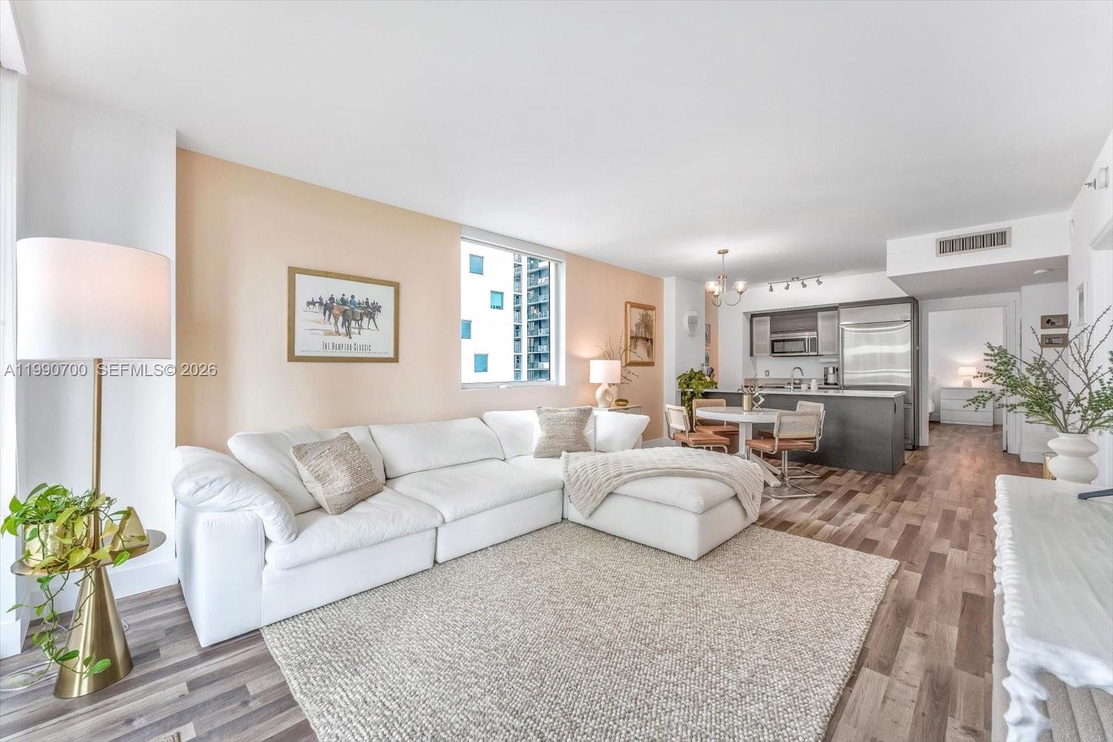 A living room features a white sectional sofa, a textured rug, and an open kitchen — 500 Brickell Ave # 1810, Miami FL 33131, MIAMI, FL