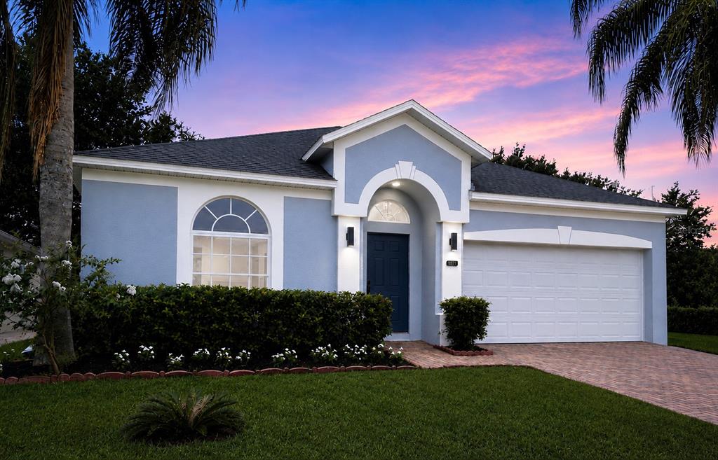 A light blue single-story house with a two-car garage and a paved driveway at dusk — 9917 SHADOW CREEK DRIVE, ORLANDO, FL