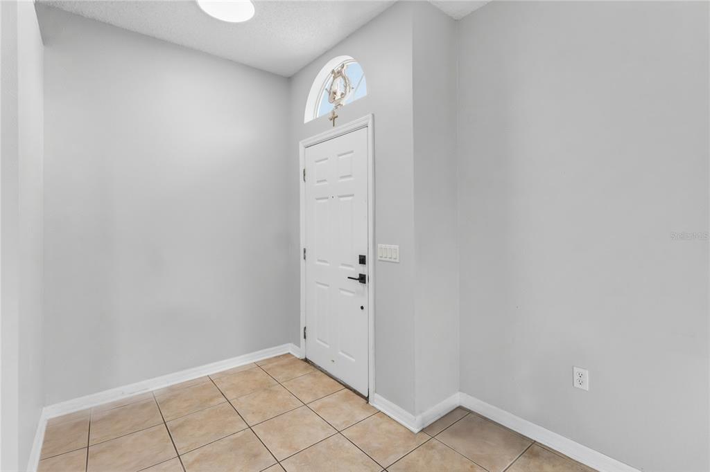 An entryway with light gray walls, tile flooring, a white front door, and an arched window — 9917 SHADOW CREEK DRIVE, ORLANDO, FL