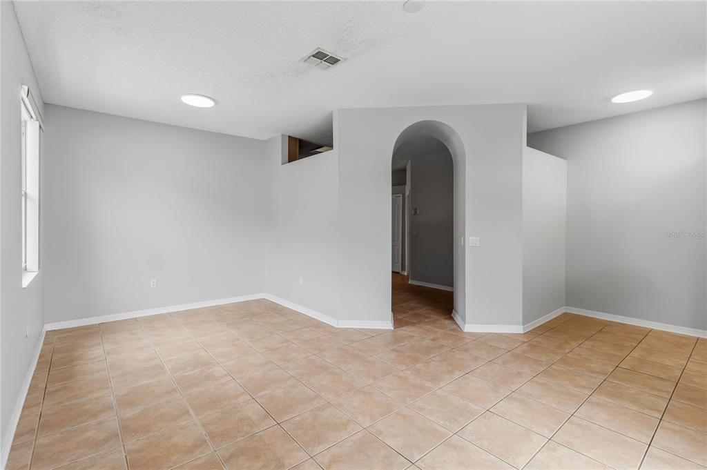 An empty room with light gray walls, tile flooring, and an arched doorway — 9917 SHADOW CREEK DRIVE, ORLANDO, FL