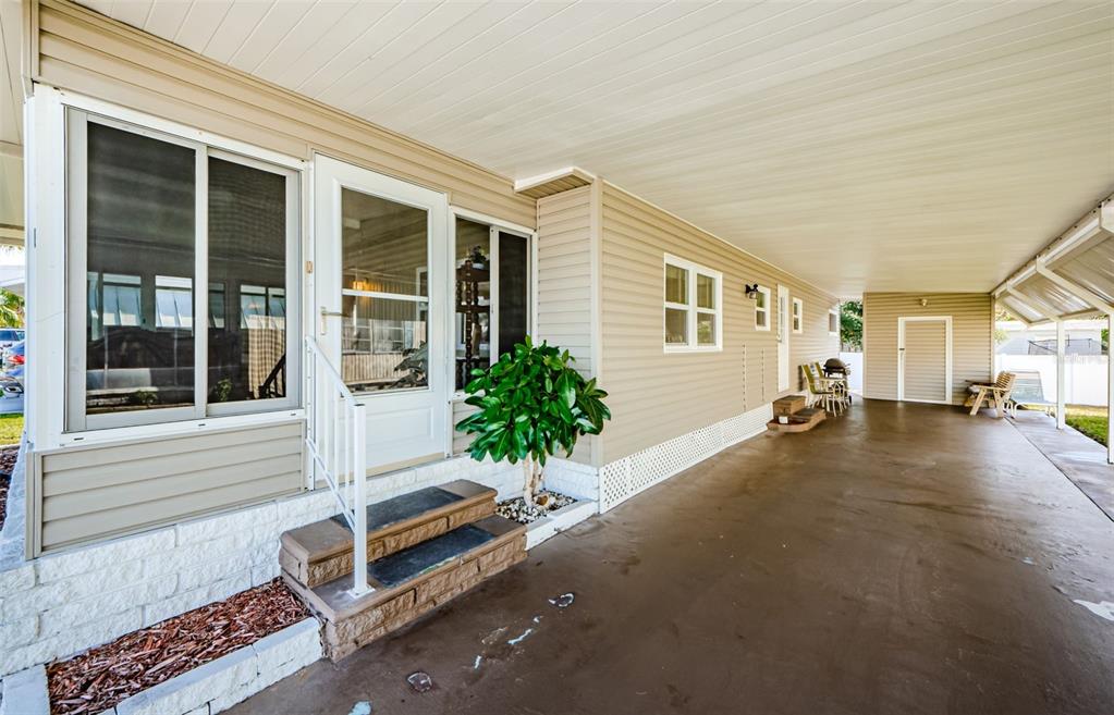 A beige mobile home exterior features a covered carport, a front door, and sliding windows — 39820 US HIGHWAY 19 N UNIT 15, TARPON SPRINGS, FL