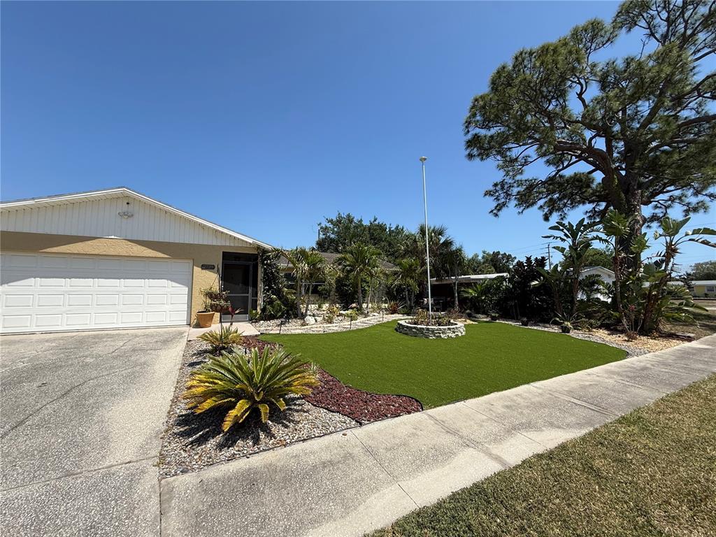 A single-story house with a white garage door, artificial turf lawn, and a flagpole — 2729 NODOSA DRIVE, SARASOTA, FL