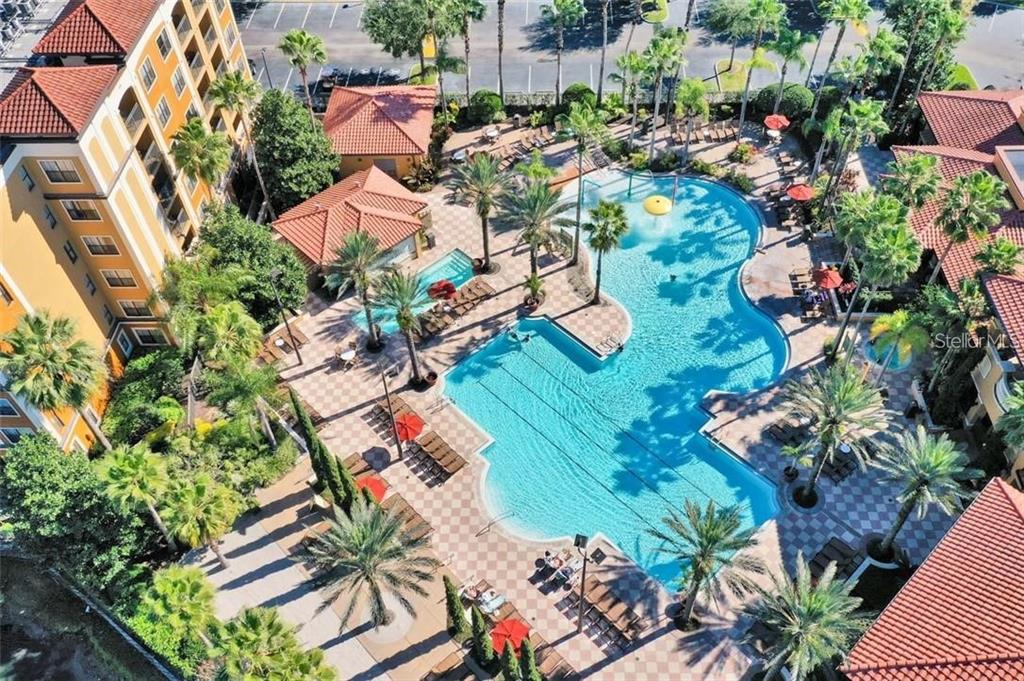 An aerial view shows a large resort-style swimming pool surrounded by palm trees and buildings — 12527 FLORIDAYS RESORT DRIVE UNIT 512E, ORLANDO, FL