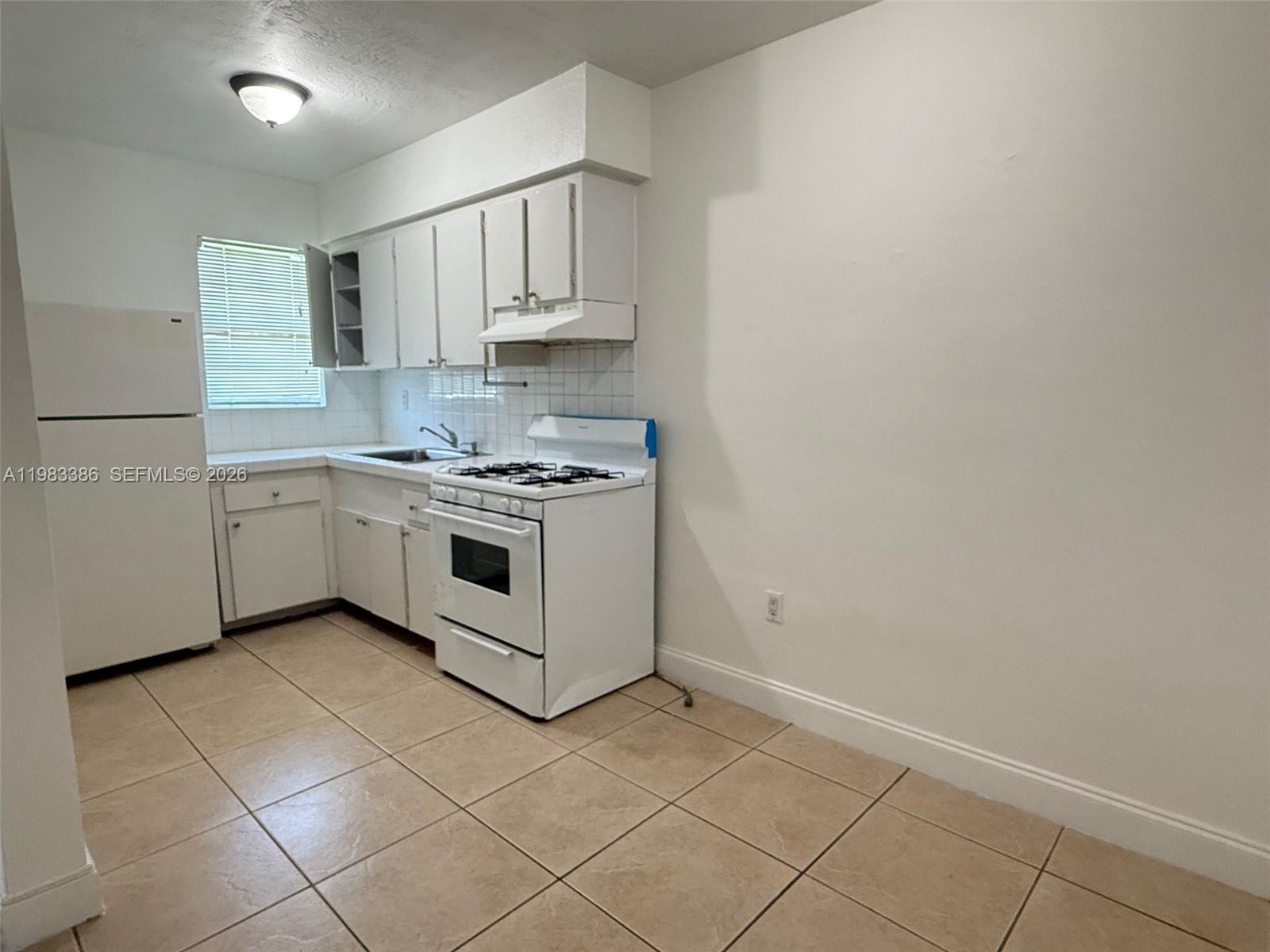 A kitchen features white cabinets, a white stove, a refrigerator, and beige tile flooring — 4300 SW 67th Ave # 38, Miami FL 33155, MIAMI, FL