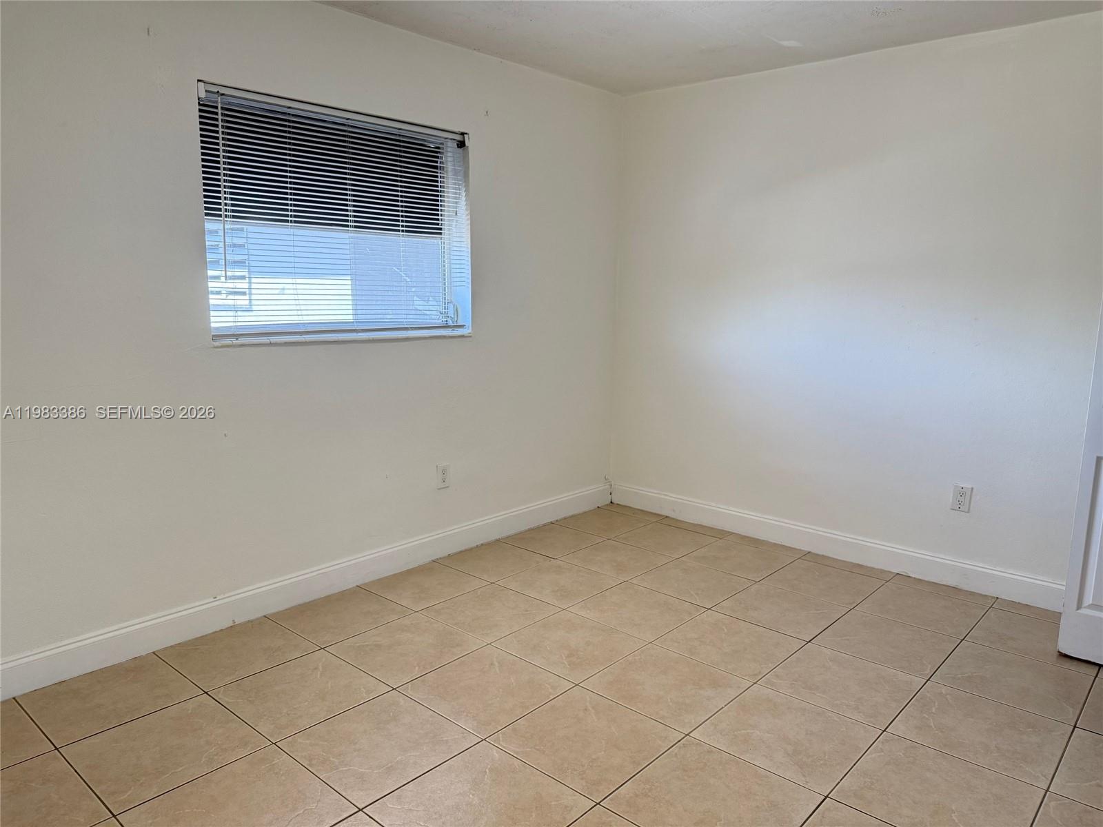 An empty room features white walls, beige tile flooring, and a single window with blinds — 4300 SW 67th Ave # 38, Miami FL 33155, MIAMI, FL