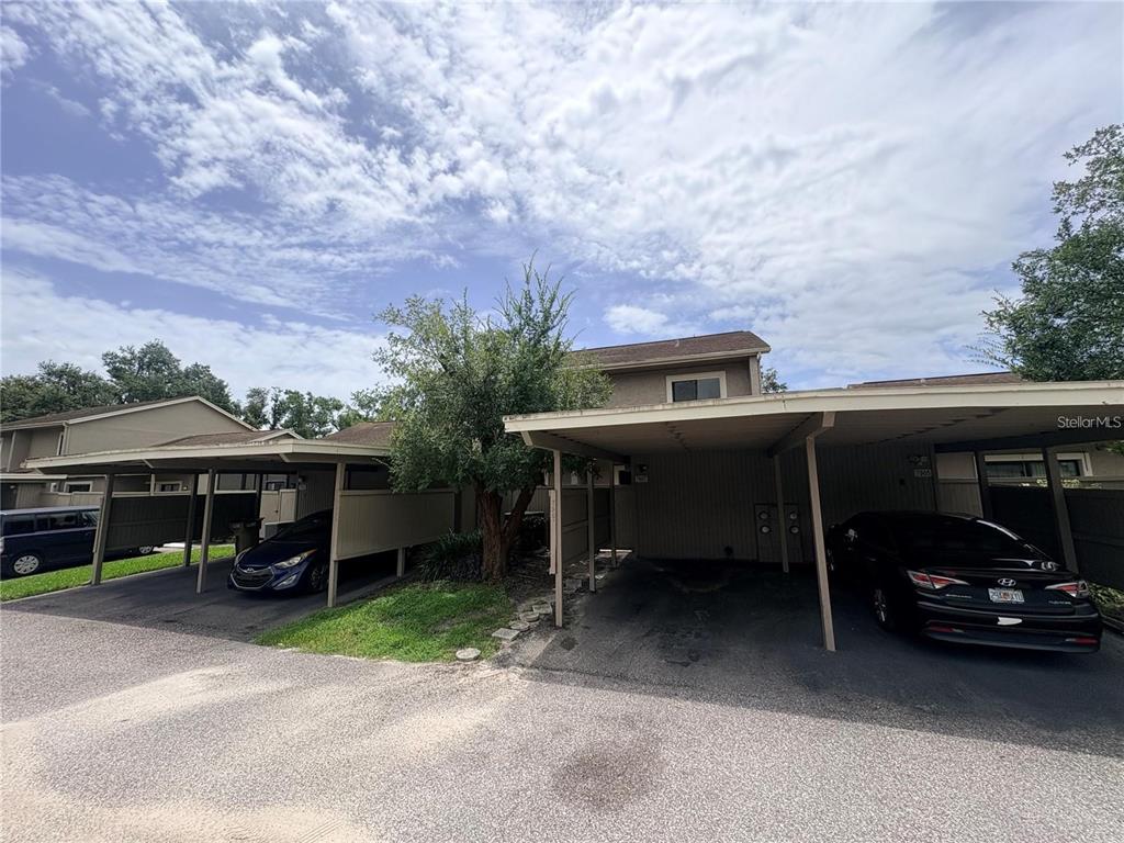 A two-story building with covered carports and parked vehicles under a cloudy sky — 7907 TANGERINE DRIVE, TAMPA, FL