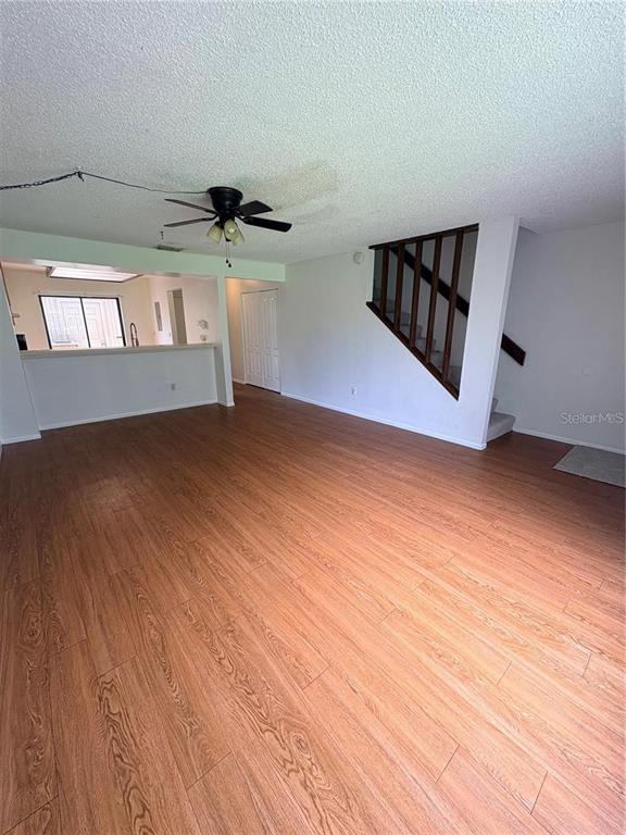 A living room features wood-look laminate flooring, a ceiling fan, and an open staircase — 7907 TANGERINE DRIVE, TAMPA, FL