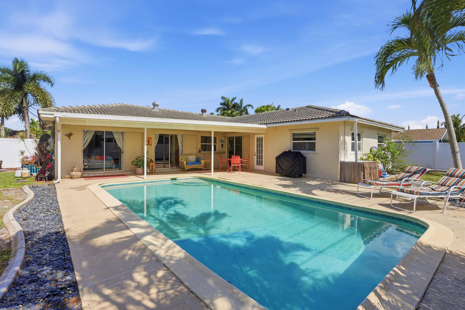 A backyard features a rectangular swimming pool, a covered patio, and lounge chairs on a deck — 106 Orchard Ridge Lane, Boca Raton FL 33431, BOCA RATON, FL