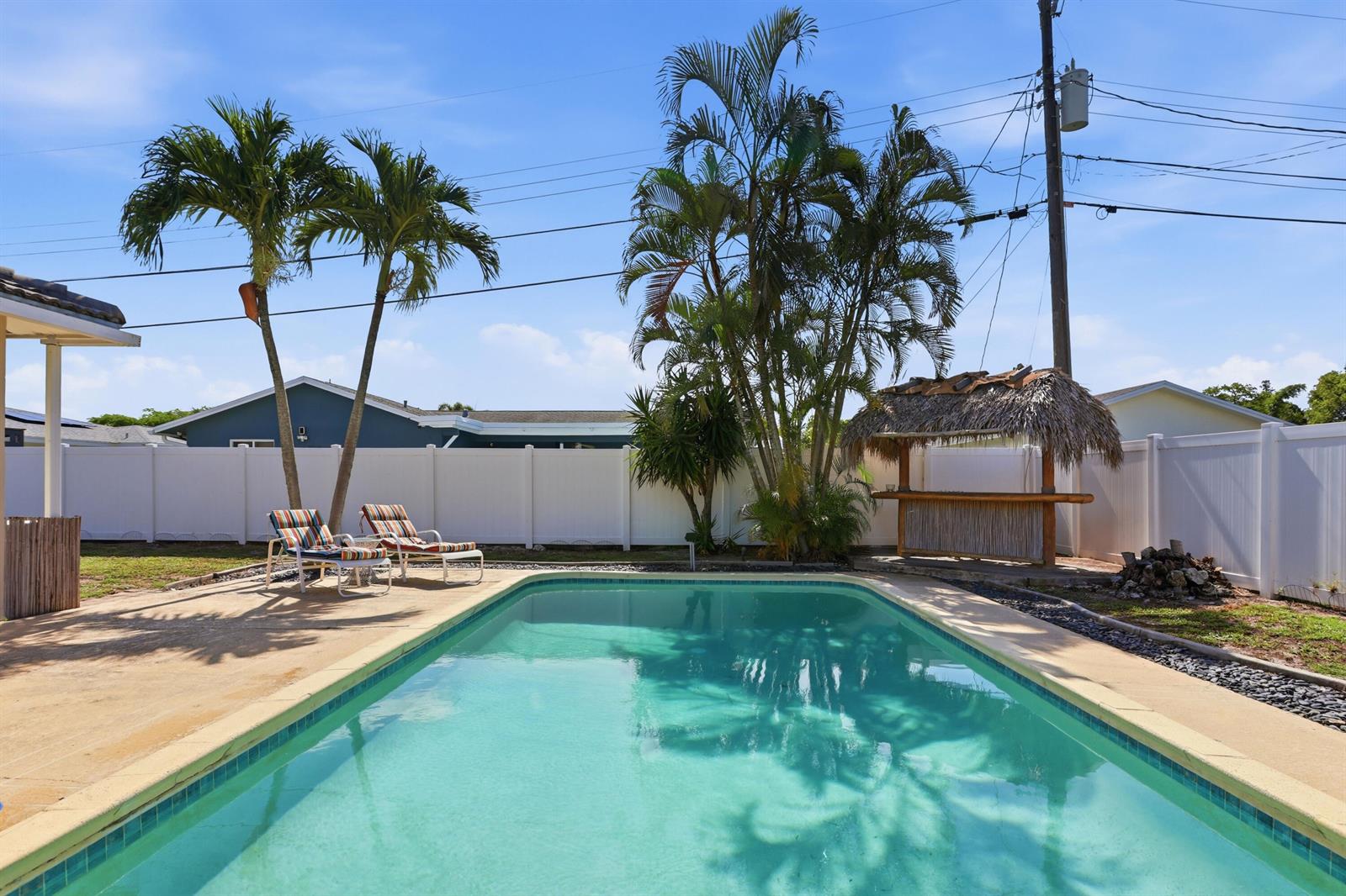 A backyard swimming pool features two lounge chairs, palm trees, and a tiki bar — 106 Orchard Ridge Lane, Boca Raton FL 33431, BOCA RATON, FL