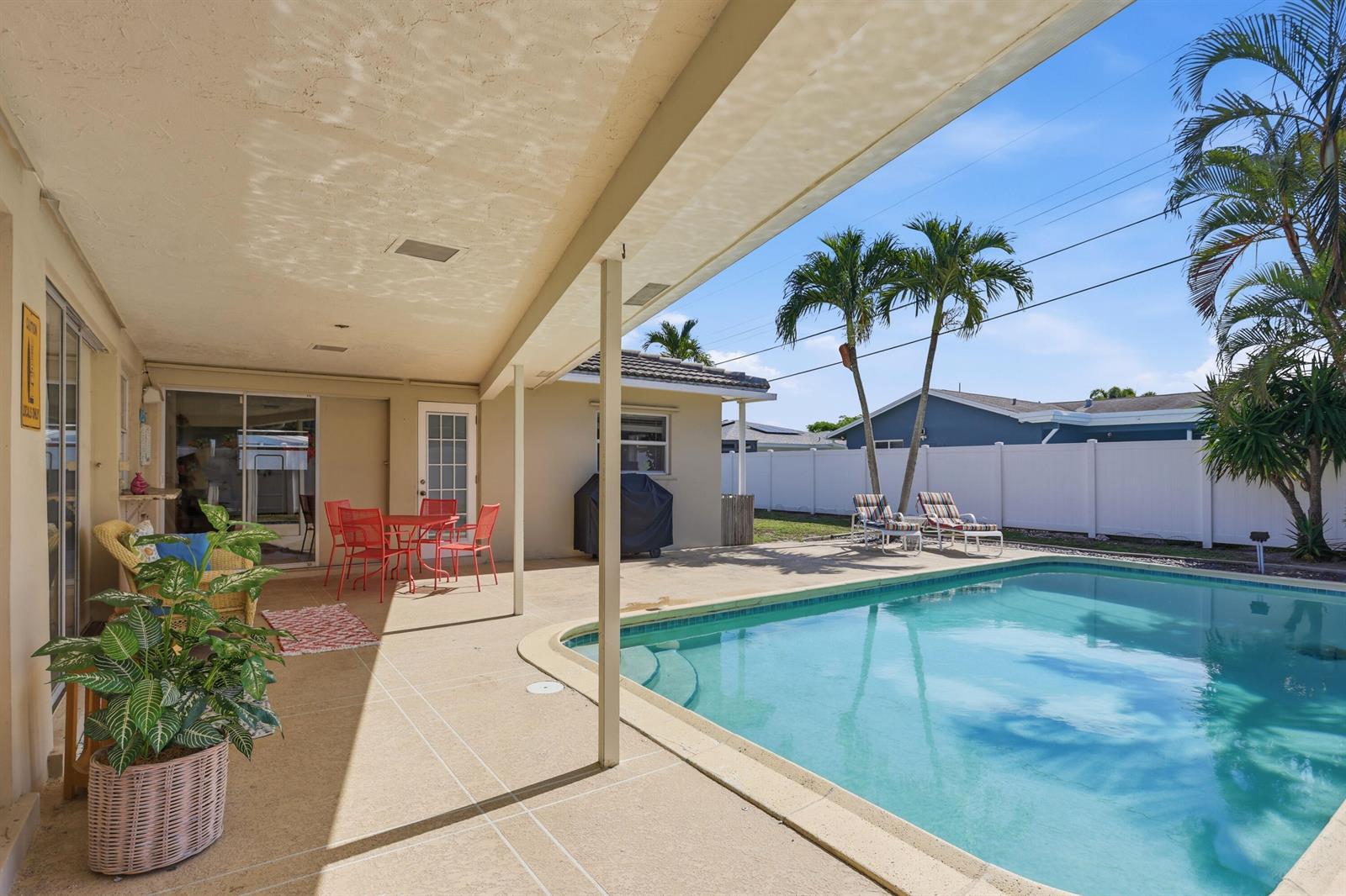A covered patio overlooks a swimming pool in a backyard with palm trees and fencing — 106 Orchard Ridge Lane, Boca Raton FL 33431, BOCA RATON, FL