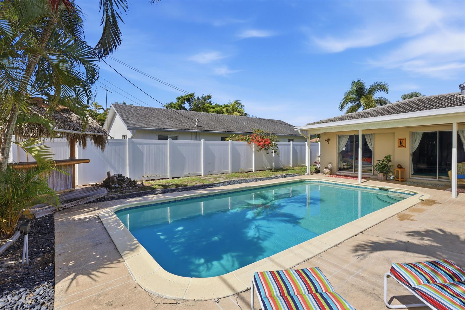 A backyard features a rectangular swimming pool, a tiki bar, and a white privacy fence — 106 Orchard Ridge Lane, Boca Raton FL 33431, BOCA RATON, FL