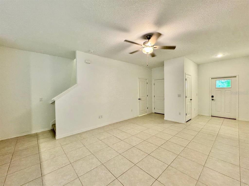 An empty room with white walls, tile flooring, a ceiling fan, and a front door — 17657 NECTAR FLUME DRIVE, LAND O LAKES, FL
