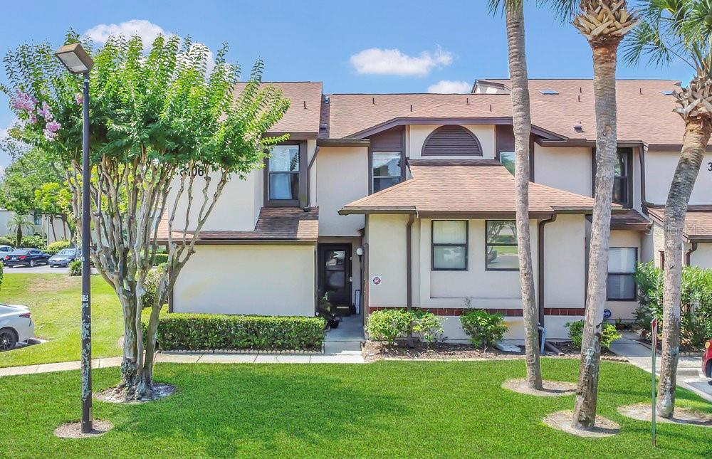 A two-story townhouse with a beige stucco exterior, brown trim, and a small front lawn — 3106 S SEMORAN BOULEVARD UNIT P-2, ORLANDO, FL