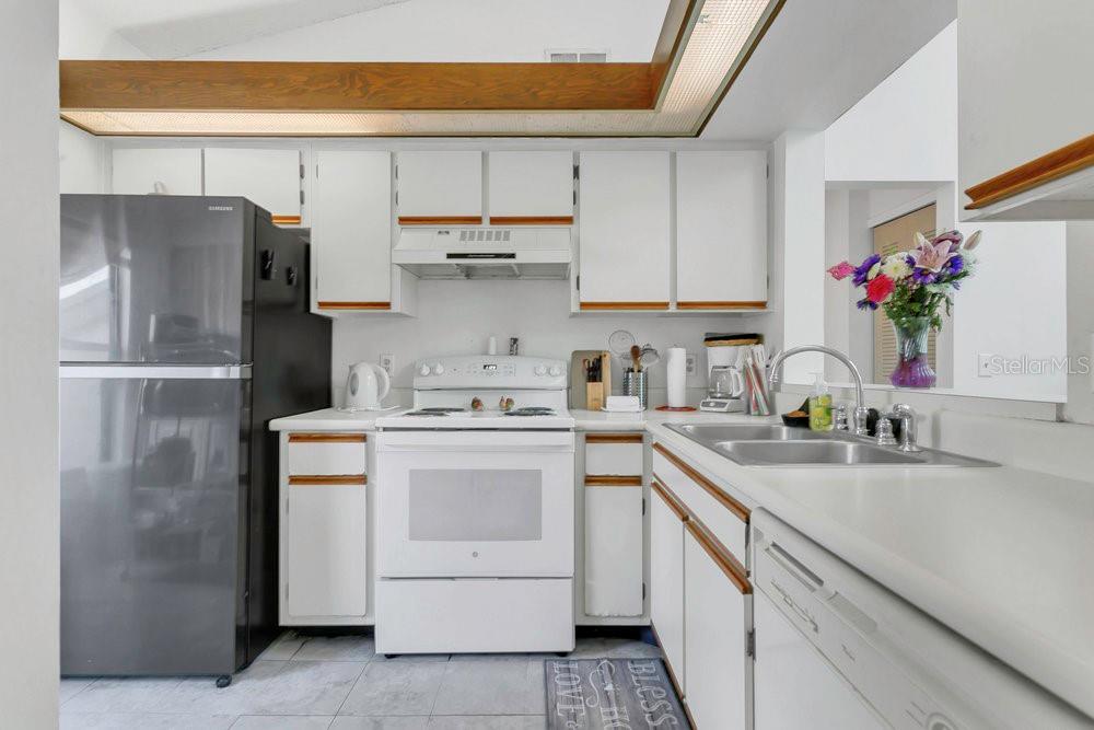 A kitchen featuring white cabinets, a black refrigerator, a white stove, and light-colored countertops — 3106 S SEMORAN BOULEVARD UNIT P-2, ORLANDO, FL